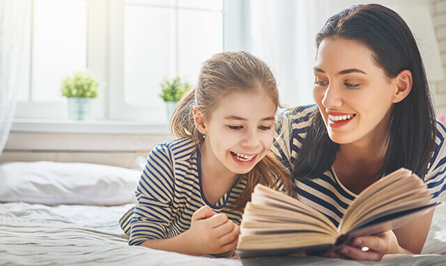 Mom reading to her daughter in bed