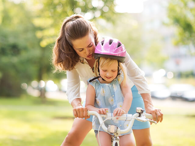 Mom helps daughter ride a bike
